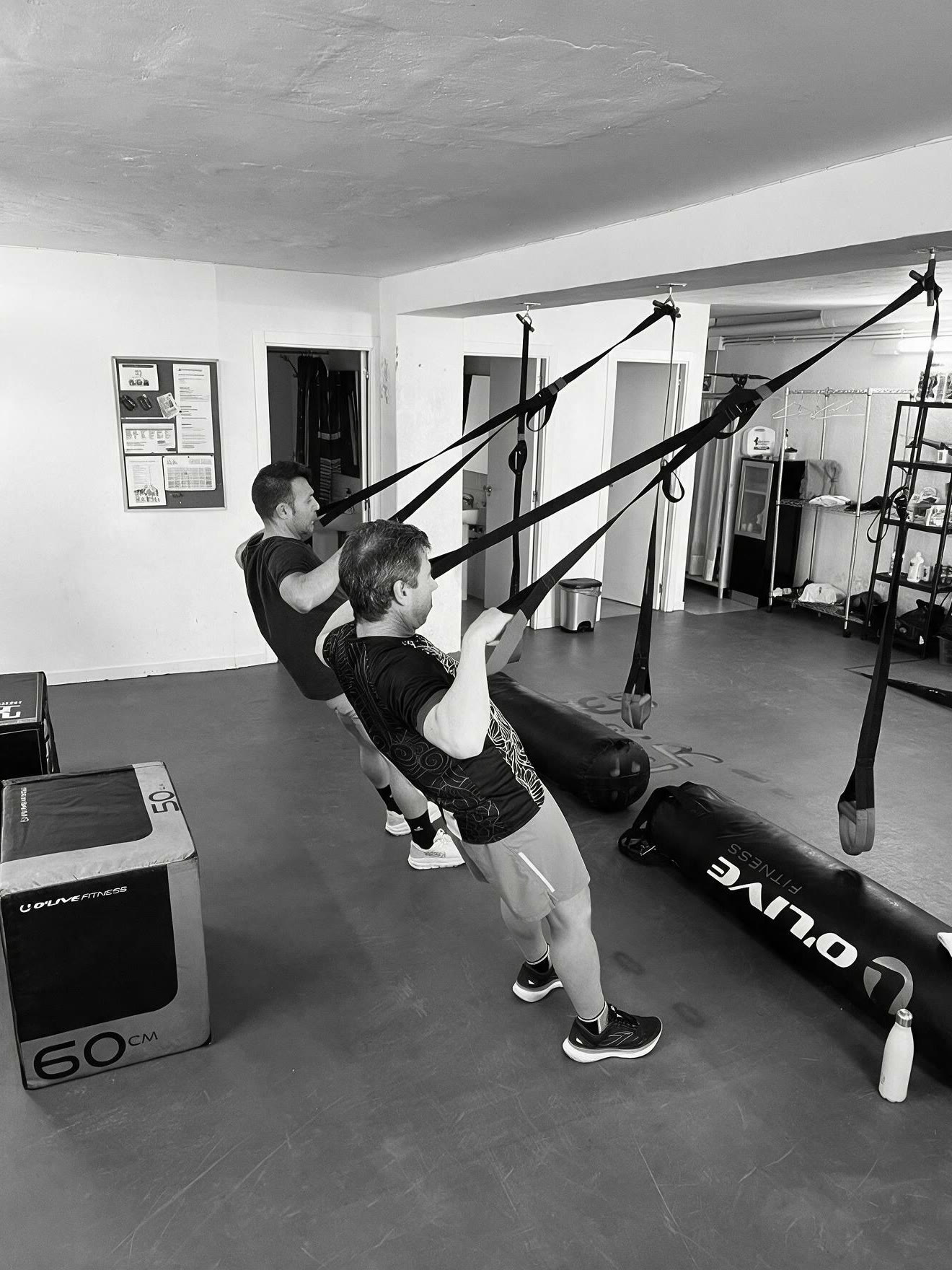 Ramon Torné corregint la posició d'un alumne fent rem amb TRX